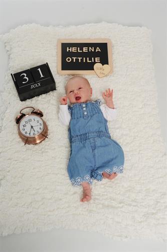 ein Baby, das auf einem Bett mit einer Uhr und einem Schild liegt